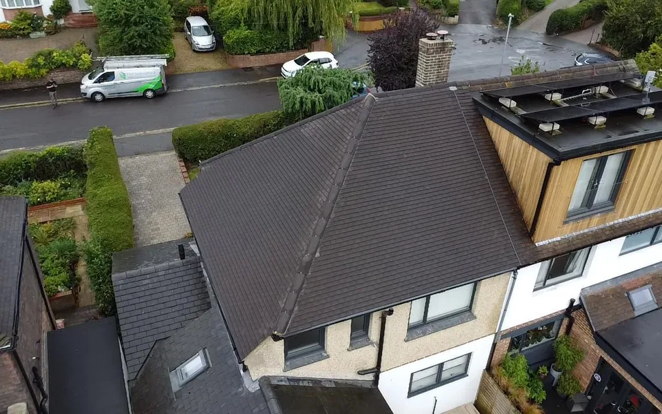 Drone view of a brown tile hipped roof on a semi with a timber-clad dormer topped by a black flat roof