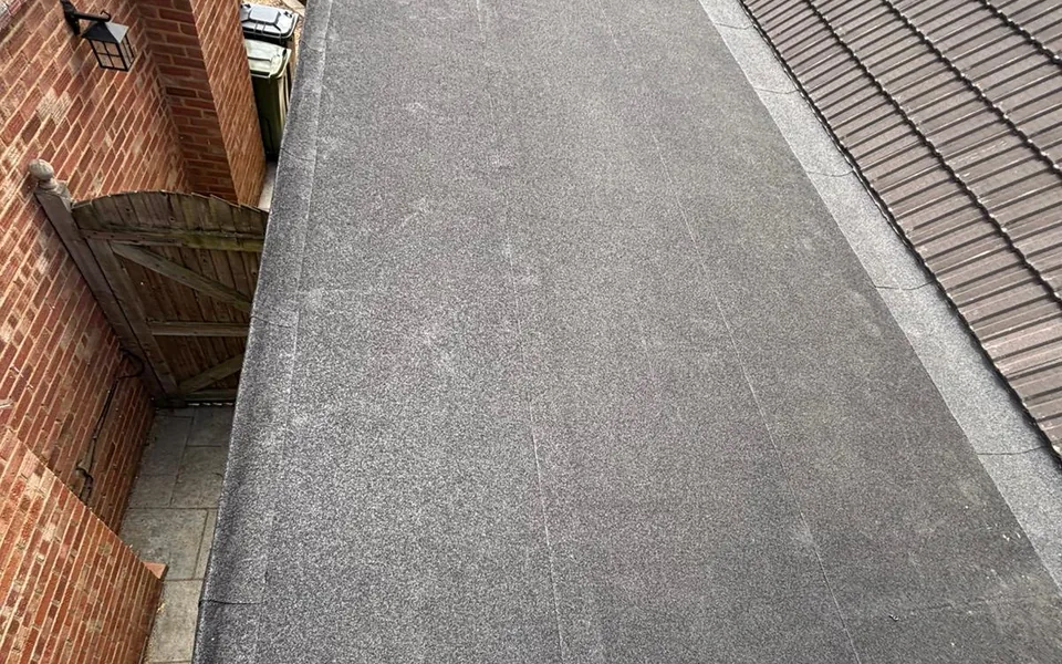 New flat roof with a mineral finish running alongside a tiled roof slope