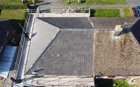 Drone view of a semi re-roofed in new grey concrete tile, beside the neighbour's original mossy roof