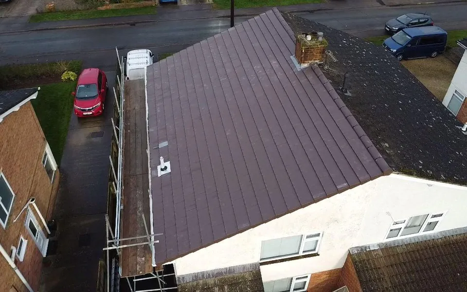 Drone view of a semi-detached house with a new concrete tile roof and scaffold down the side
